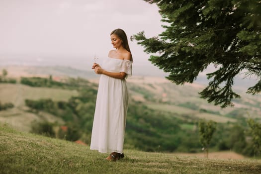 Young pregnant woman relaxing outside in nature at summer day