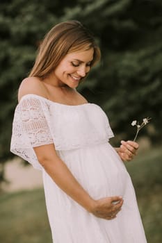 Young pregnant woman relaxing outside in nature at summer day