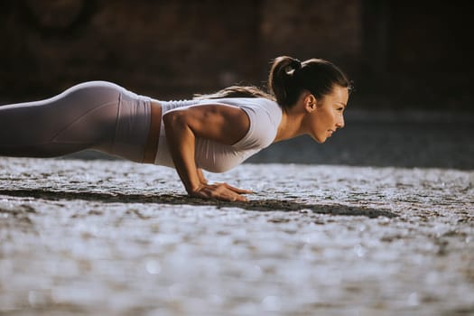 Pretty young woman doing puhsups on the street