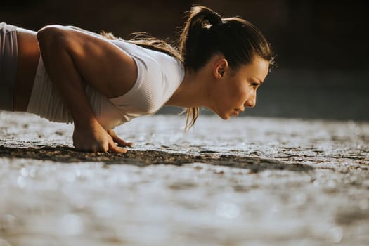 Pretty young woman doing puhsups on the street