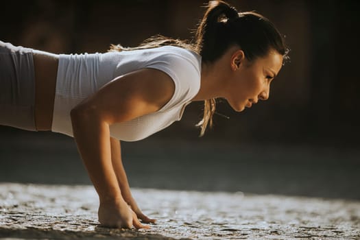 Pretty young woman doing puhsups on the street
