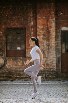 Pretty young woman warming before running in the urban environment
