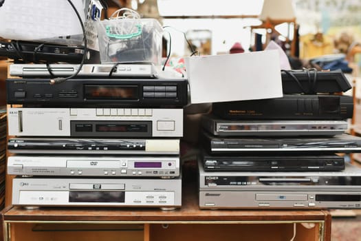 VERONA, ITALY - MARCH 04, 2023: Vintage Retro audio video devices on a flea market. Stack of many DVD CD players