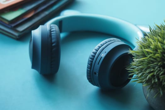 Bright teal surface features headphones, a small plant, and stacked books.