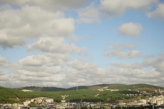 Clouds float over a lush green landscape featuring a quaint town below.