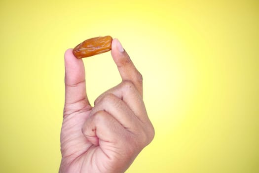 A hand displays a single date fruit showcasing its rich texture.