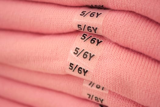 Soft pink garments labeled for toddler sizes are neatly arranged in stacks.