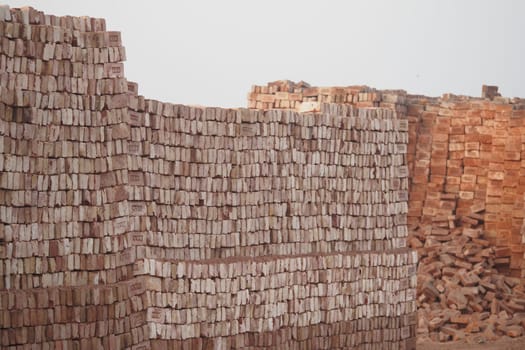Stacked bricks are organized at a construction site in daylight.