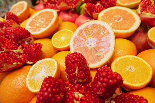 Colorful arrangement of sliced citrus and whole pomegranates in market.