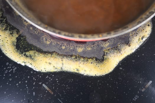 A boiling pot causing spills and stains on the cooking surface.