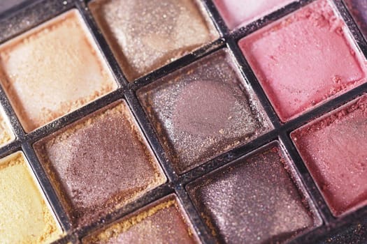 Close-up of a makeup palette displaying various shimmering shades and textures.