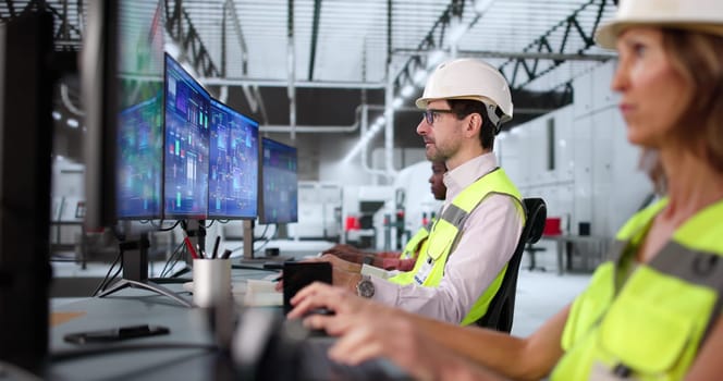 Multiracial team using Scada automation software in modern semiconductor factory.
