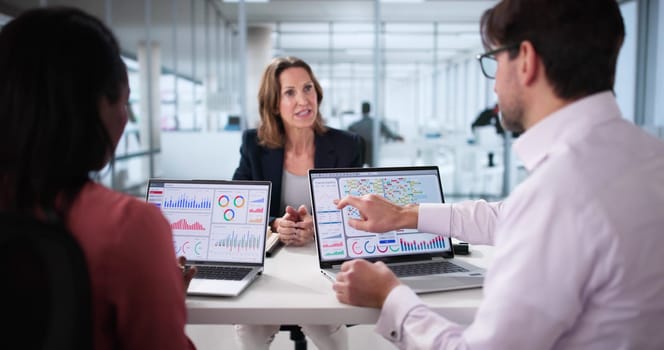 Analyzing data on analytics dashboard during multicultural team meeting in office.