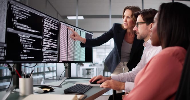 Busy professionals work together on diverse software coding projects in office.