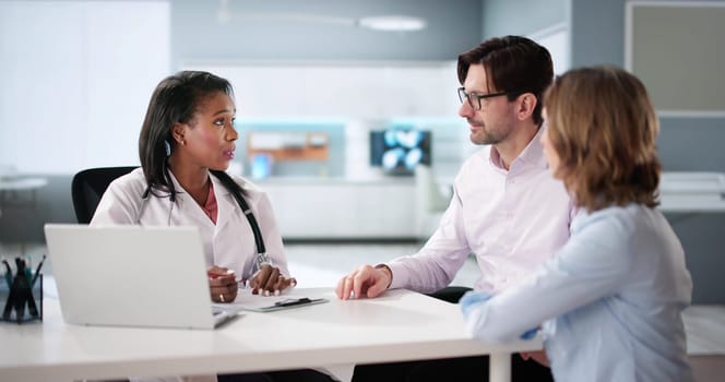 African pregnant couple happy at doctor's office discussing pregnancy.