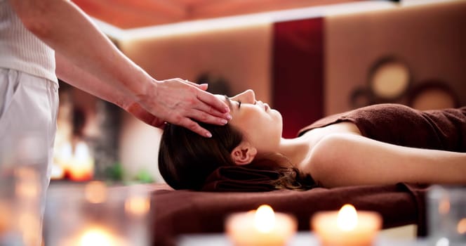 Relaxing spa day with facial massage by skilled chiropractor. Young woman undergoing traditional Chinese acupuncture treatment