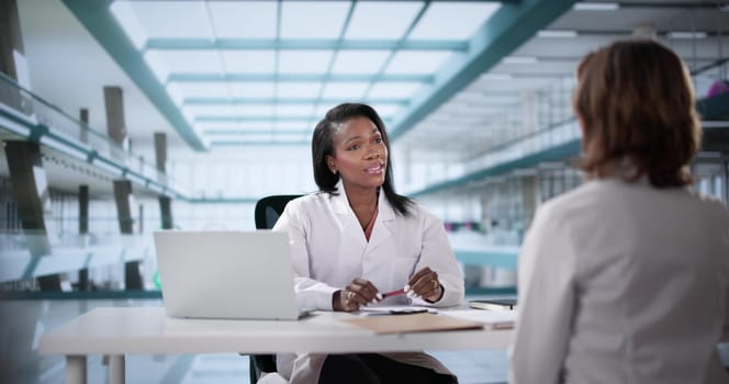 Unhappy doctor sits in a disciplinary meeting with black office backdrop.   Possible professions: doctor, nurse, dentist, police officer, therapist.