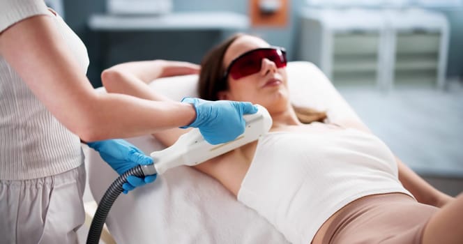 Woman receiving laser hair removal treatment at beauty salon spa.