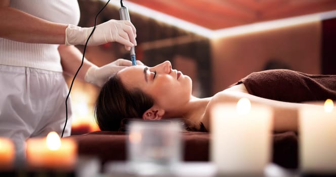 Doctor performing microneedling mesotherapy on woman at beauty clinic.