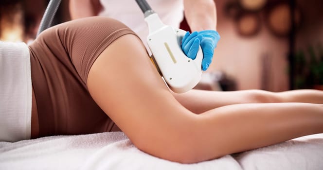 Woman receiving laser hair removal treatment at spa by beautician.