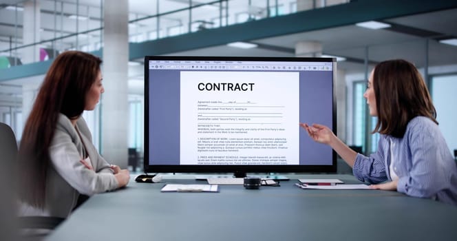 Corporate lawyer assisting female colleague with contract mediation and review.