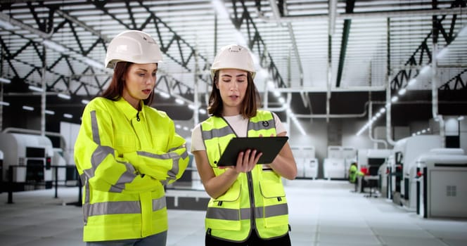 Female engineer inspects factory using tablet for OSHA inspection report.