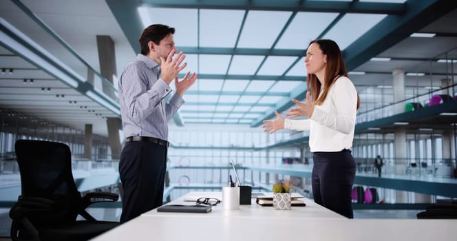 Office Conflict: A Man and Woman Argue at Their Desks.