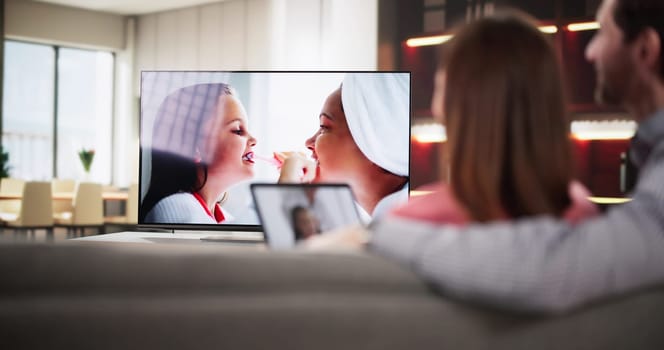 Man watching internet streaming from connected tablet to television at home, consultant, marketer, technology specialist, media integration.