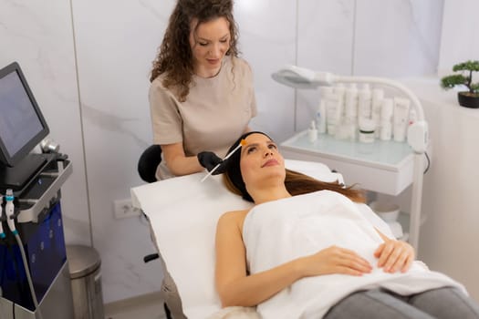 A woman enjoys a luxurious skincare treatment, lying on a treatment bed while a skilled aesthetician gently applies a soothing serum to her face in a serene spa environment.