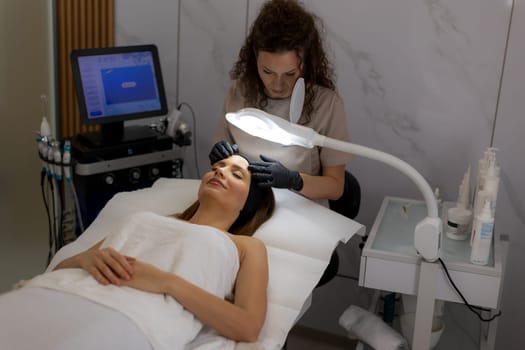 Under soft lighting, a skilled skincare specialist gently performs a treatment on a client lying comfortably on a treatment bed, emphasizing relaxation and rejuvenation.