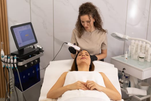 A skilled therapist gently uses an ultrasonic facial massager on a client's forehead, enhancing relaxation and skincare in a tranquil spa environment during a rejuvenating session.