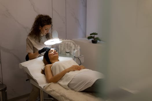 Under soft lighting, a skilled skincare specialist gently performs a treatment on a client lying comfortably on a treatment bed, emphasizing relaxation and rejuvenation.