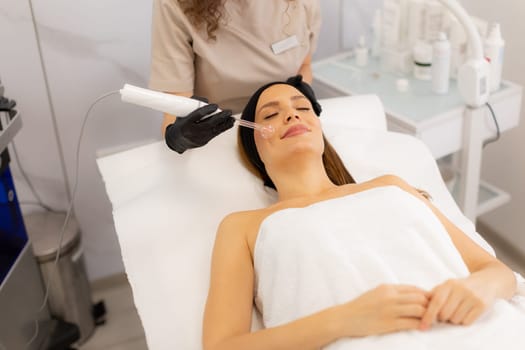 A skilled therapist employs high frequency therapy on a client's face, promoting skin health and relaxation in a tranquil spa environment. The atmosphere radiates comfort and care.