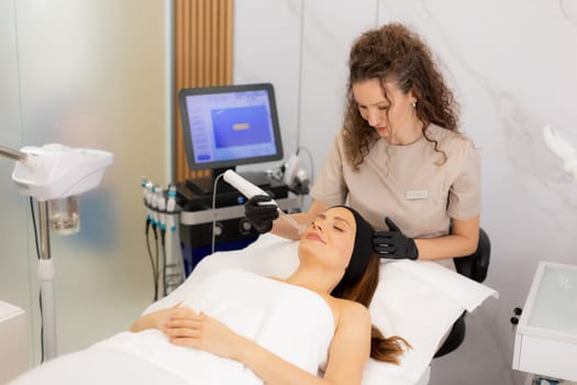 A skilled therapist employs high frequency therapy on a client's face, promoting skin health and relaxation in a tranquil spa environment. The atmosphere radiates comfort and care.