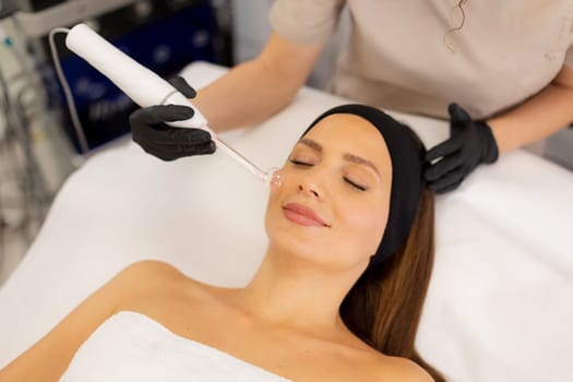 A therapist administers a high frequency therapy treatment, utilizing a glass electrode over a client's face. The process aims to refresh and revitalize the skin in a tranquil setting.