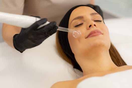 A skilled therapist employs high frequency therapy on a client's face, promoting skin health and relaxation in a tranquil spa environment. The atmosphere radiates comfort and care.