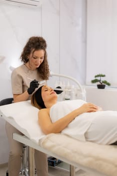 In a serene spa room, a skilled aesthetician applies serum retinol to a relaxed client, focusing on rejuvenating her skin for a youthful glow during the luxurious session.