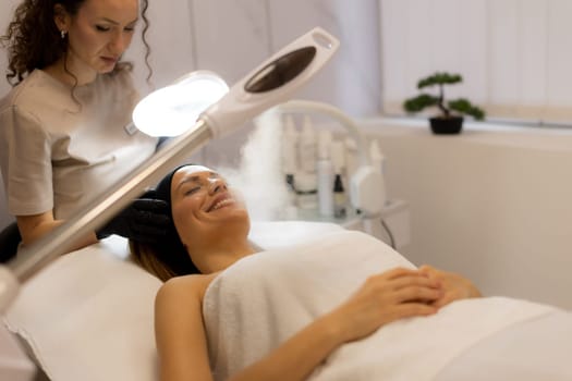 A tranquil spa setting features a woman enjoying a facial treatment, with mist enveloping her face. The atmosphere promotes relaxation and skincare rejuvenation.