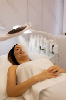 A tranquil spa setting features a woman enjoying a facial treatment, with mist enveloping her face. The atmosphere promotes relaxation and skincare rejuvenation.