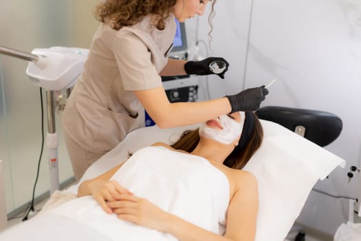 In a soothing spa setting, a patient enjoys a revitalizing facial as a professional aesthetician applies a nourishing mask, promoting relaxation and rejuvenation.