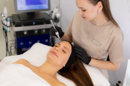 A skilled professional uses a microneedling mesotherapy device on a client in a serene clinic, focusing on skin rejuvenation and enhancing beauty. The environment is calm and sterile.