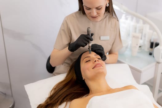 A beauty professional performs microneedling mesotherapy on a client's facial skin, promoting rejuvenation and vitality in a tranquil treatment room with soft lighting.