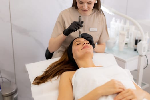A beauty professional performs microneedling mesotherapy on a client's facial skin, promoting rejuvenation and vitality in a tranquil treatment room with soft lighting.