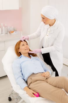 Patient relaxes on a comfortable treatment bed while a skilled practitioner applies dermal filler to enhance facial features in a tranquil clinic environment.