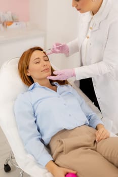 A dedicated practitioner carefully performs dermal filler therapy on a client in a bright and welcoming clinic.