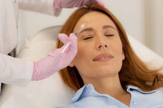Patient relaxes on a comfortable treatment bed while a skilled practitioner applies dermal filler to enhance facial features in a tranquil clinic environment.