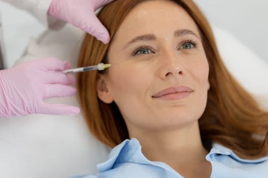Client sits comfortably in a bright clinic, smiling as a professional applies dermal filler treatment. The serene atmosphere supports relaxation and rejuvenation.