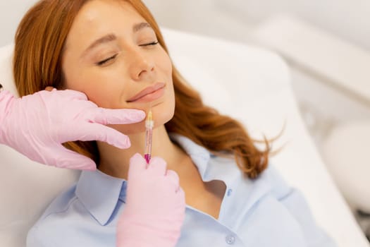 A skilled practitioner applies lip filler to a relaxed client in a calm clinic environment.