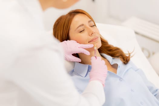 A skilled practitioner applies lip filler to a relaxed client in a calm clinic environment.
