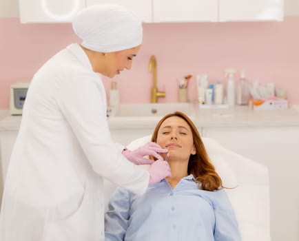 A skilled practitioner applies lip filler to a relaxed client in a calm clinic environment.